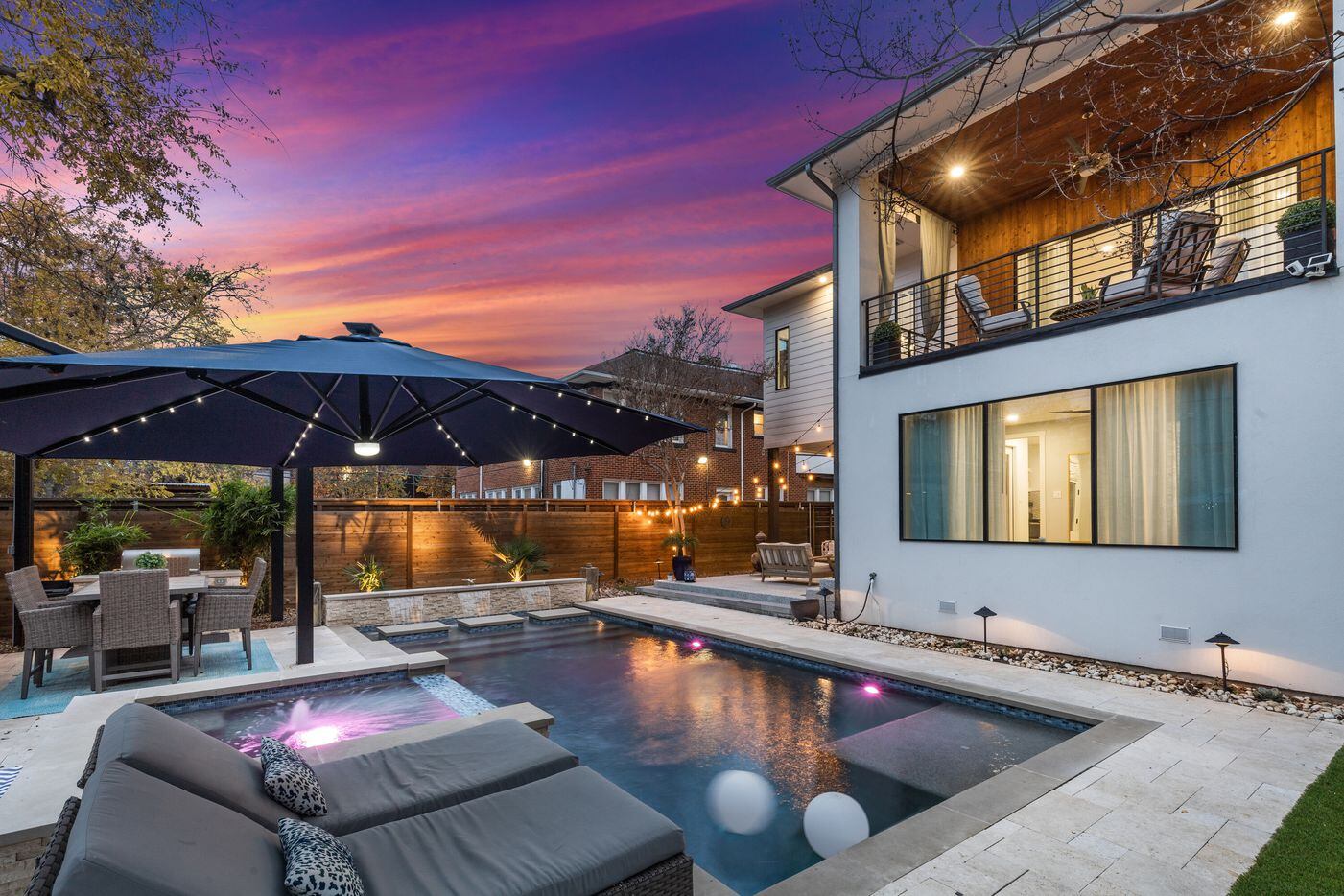 The backyard features a resort-style pool, complete with a navy blue patio umbrella, and...