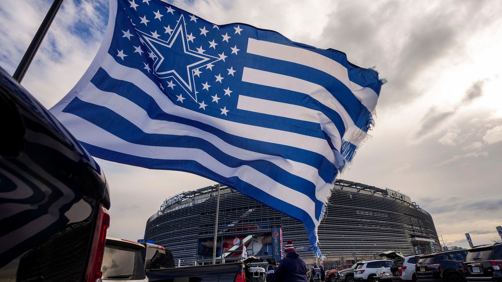 A Dallas Cowboys flag flutters in the wind as fans tailgate before an NFL football game...