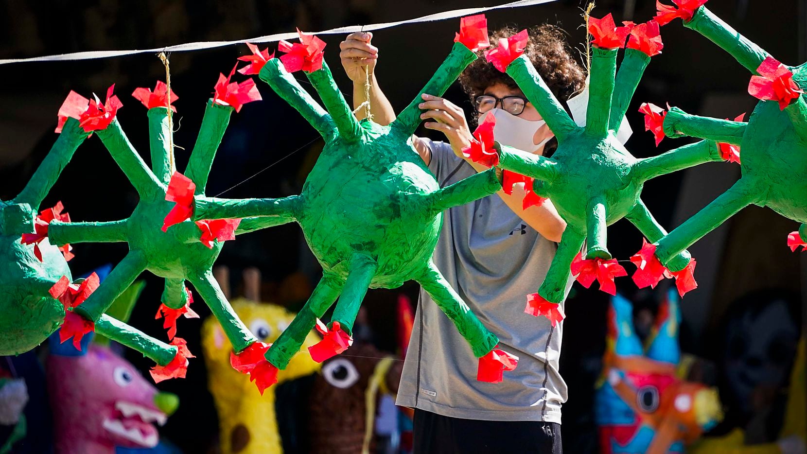 Carlos Sagero hangs a coronavirus piñata on a line after putting the finishing touches of...