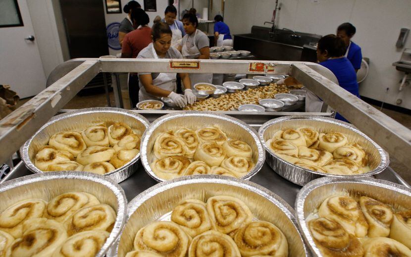 Nancy Rodriguez (center) places cinnamon rolls in a pan at RoRo's Baking Company in Dallas. 