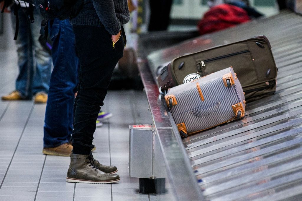 A traveler waits for his bag as luggage moves around a baggage claim at Gate C on Friday,...