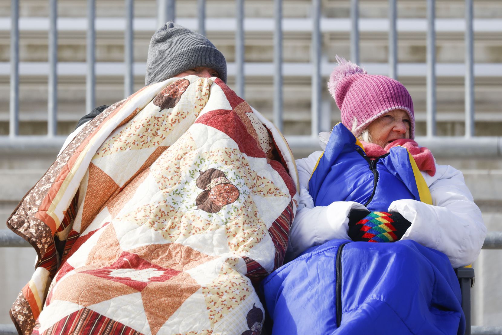 People wearing warm clothes watch a soccer game between South Grand Prairie High School and...