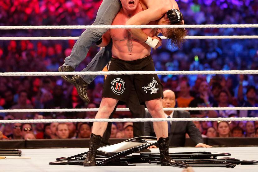 Brock Lesnar, in black shorts, wrestles Dean Ambrose during WrestleMania 32 at AT&T Stadium...