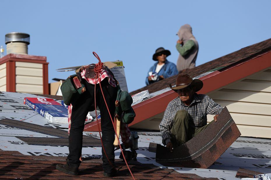 Antonio Jaramillo (der.) y otros rooferos instalan tejas en una residencia en Arlington, Texas.