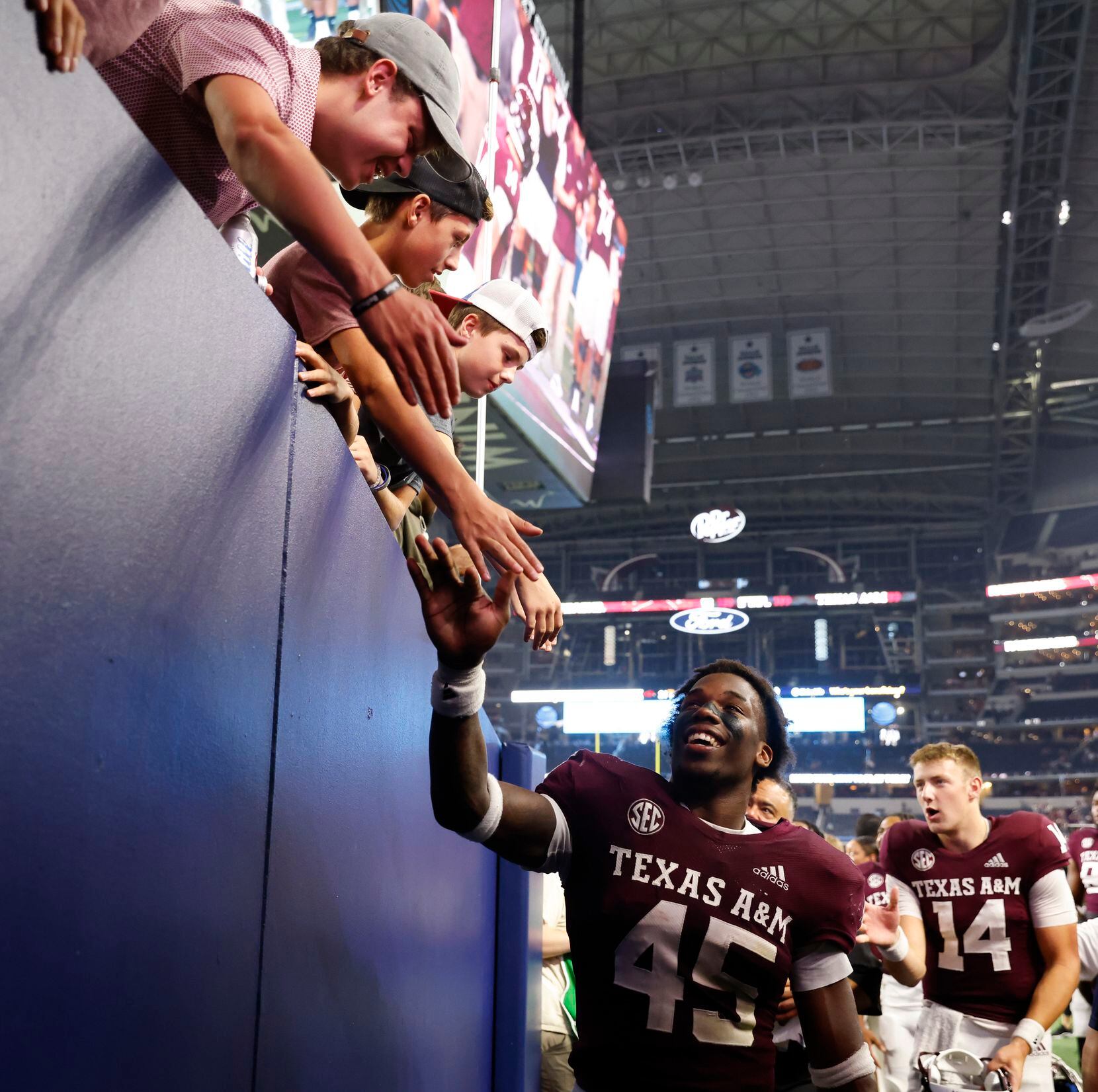Texas A&M linebacker Edgerrin Cooper (45) shakes hand with fans while entering the tunnel...