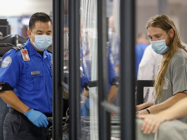 A TSA agent directs travelers at a security checkpoint at DFW International Airport.