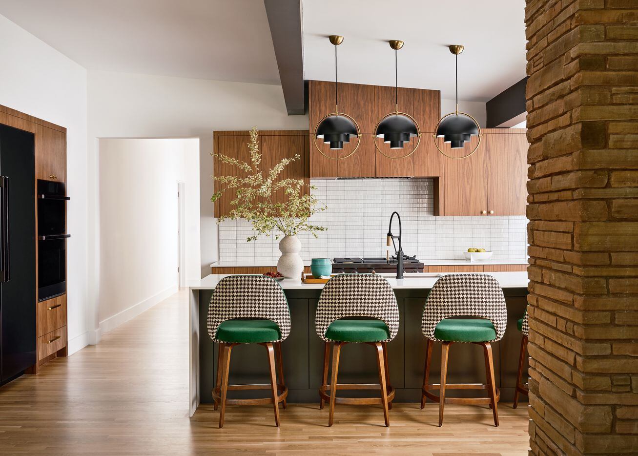 A kitchen features walnut cabinetry, a large island with barstools, and ceramic vases.