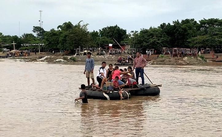 Un grupo de personas cruzan en una balsa el Río Suchiate entre Chiapas, México y...