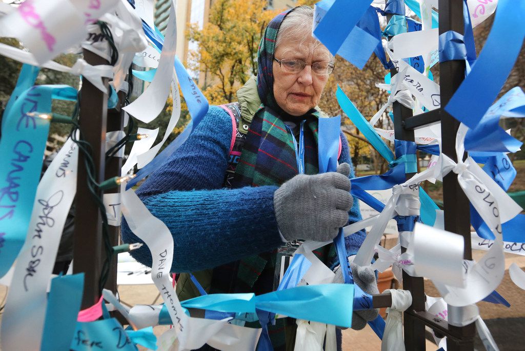 Karen Rosenkrans of Dallas ties a ribbon on a memorial in honor of her father, who served in...