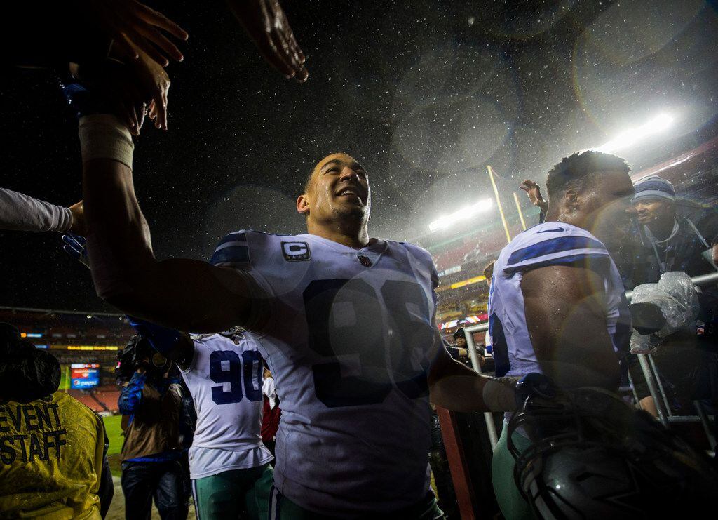 Dallas Cowboys defensive end Tyrone Crawford (98) high-fives fans as he walks off the field...