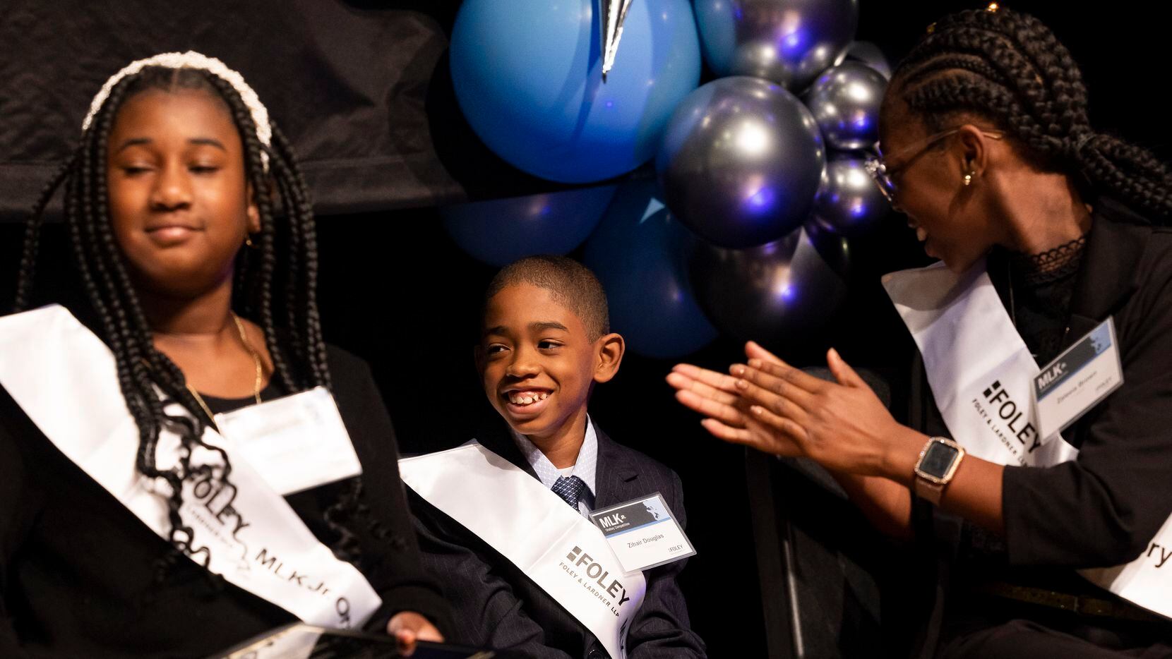 Zihair Douglas (center), a fifth grader at T.L. Marsalis Elementary STEAM Academy, reacts to...