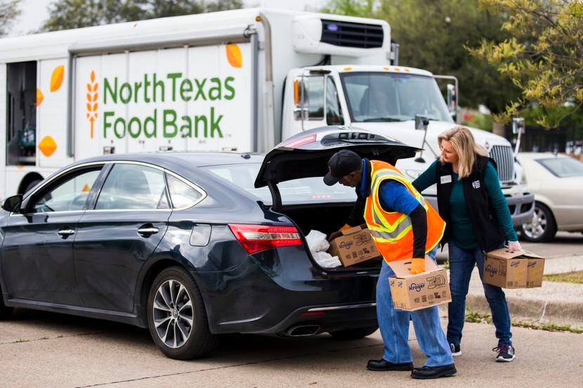 Anthony Devers, un voluntario del North Texas Bank, colocan cajas de alimentos en un...