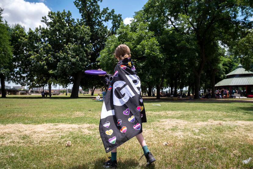 Alex Austin, 11, wears an LGBT flag while throwing Frisbee with her parents during the LGBTQ...