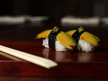 Avocado nigiri sushi. The avocado is brushed with tamari, then each piece is wrapped with a...