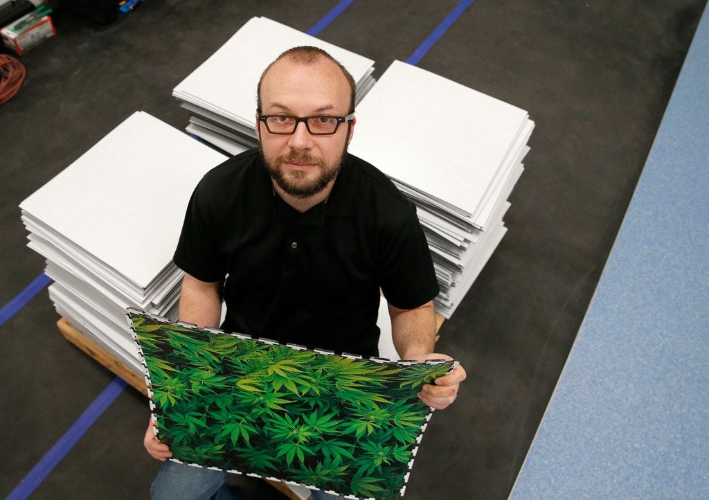 Keith Pocock, general manager of operations at GrowLife Innovations, holds luxury vinyl tile that has a photo of cannabis printed on it. Pocock developed a reflective tile that helps plants grow indoors.
