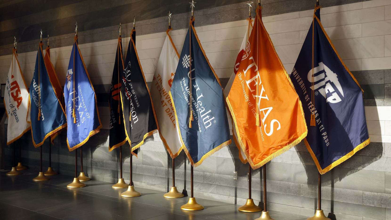Flags representing the many campuses in the University of Texas system are on display in the...