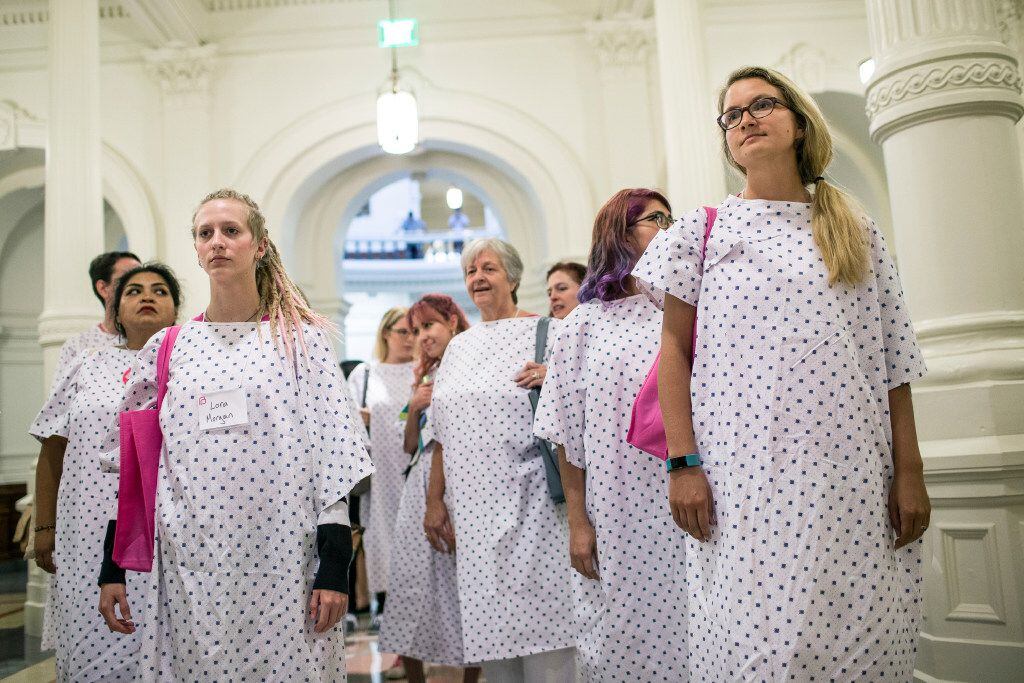 Planned Parenthood supporters, dressed in hospital gowns, gather outside of the governor's...