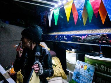 Kim Henderson looks around as she smokes a cigarette in her encampment under a bridge during...