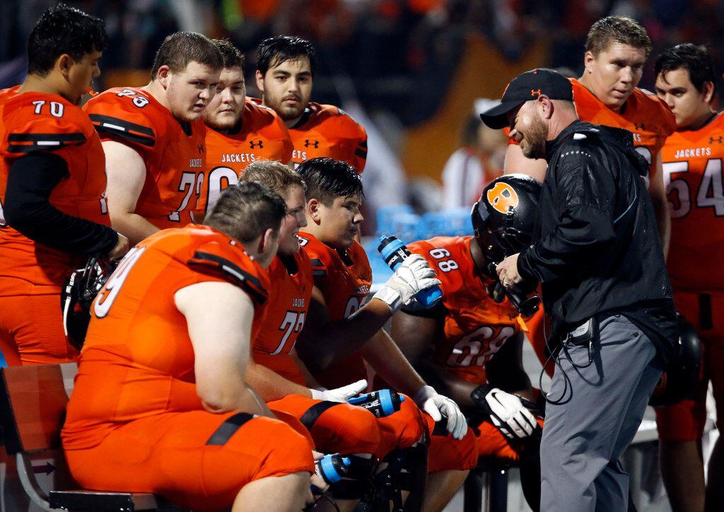 A Rockwall assistant talks with offensive linemen after a change of possession in the first...
