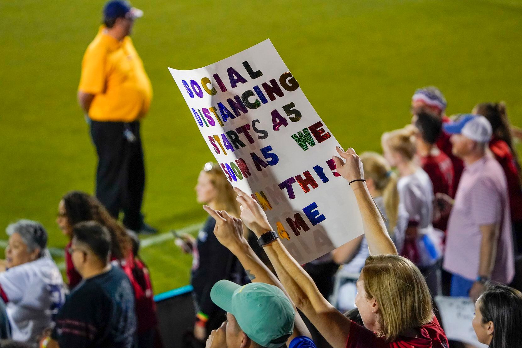 Fan Judith Tankle of Dallas holds a sign reading Òsocial distancing starts as soon as we win...