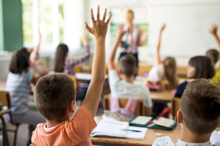Estudiantes levantan la mano durante una clase en una escuela primaria.