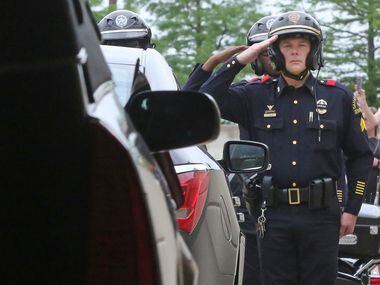 Law enforcement officers salute as the body of Dallas Officer Rogelio Santander is loaded...