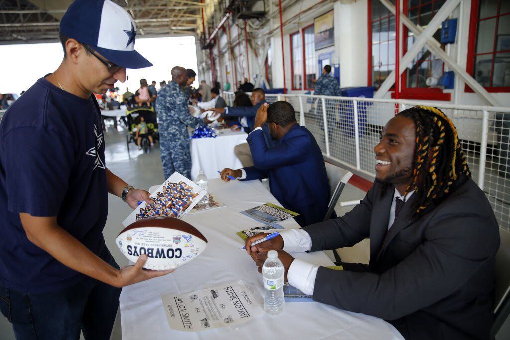 Dallas Cowboys rookie linebacker Jaylon Smith (right) signs a football during an autograph...