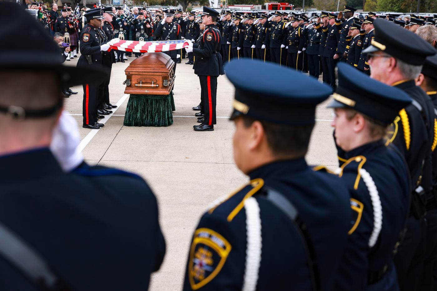 Police officers stand saluting Grand Prairie police officer Brandon P. Tsai as an American...