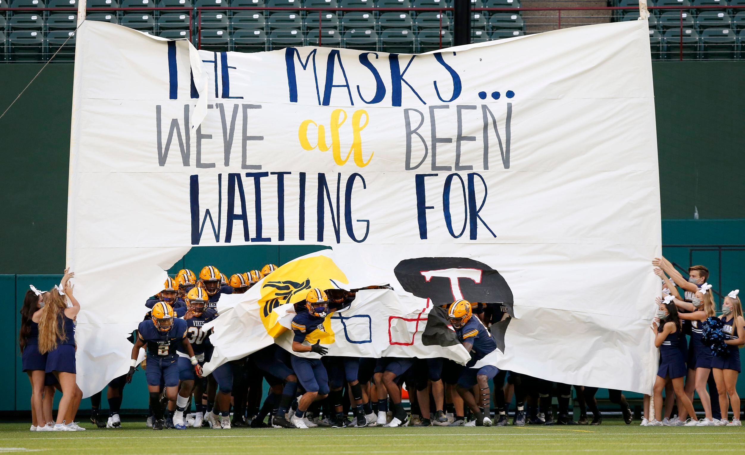 The Arlington Lamar Vikings football team breaks through a COVID-19 themed banner as they...