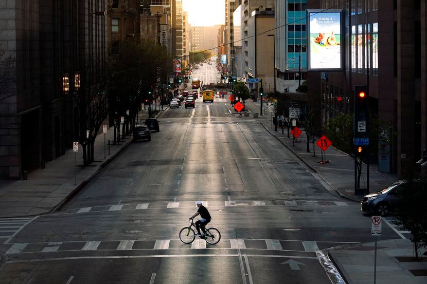 With very few cars on the street, a cyclist peddles across Elm St. in downtown Dallas,...