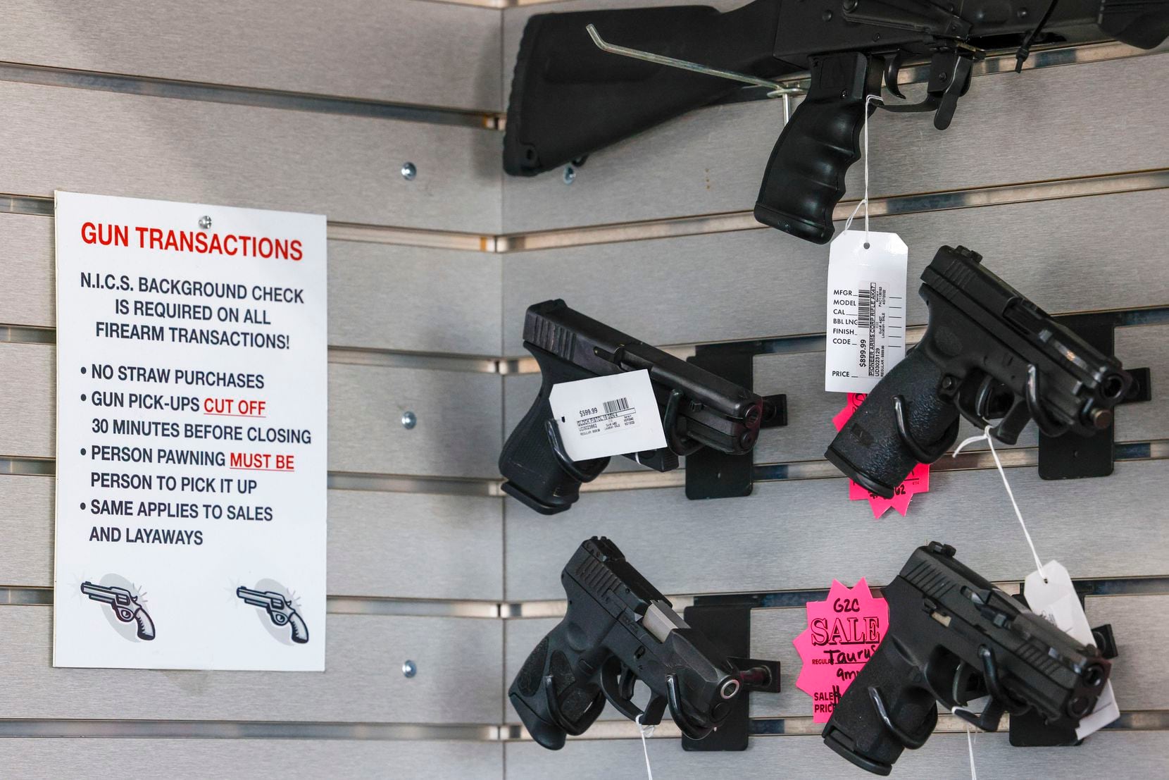 A sign displays various rules and laws for gun transactions at Uncle Dan’s Pawn Shop in...
