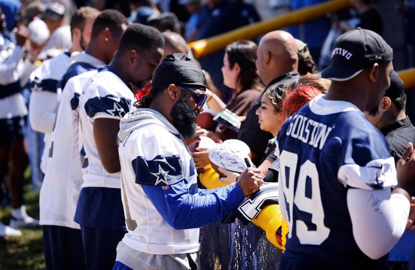Dallas Cowboys running back Ezekiel Elliott (second from right) signs autographs for...