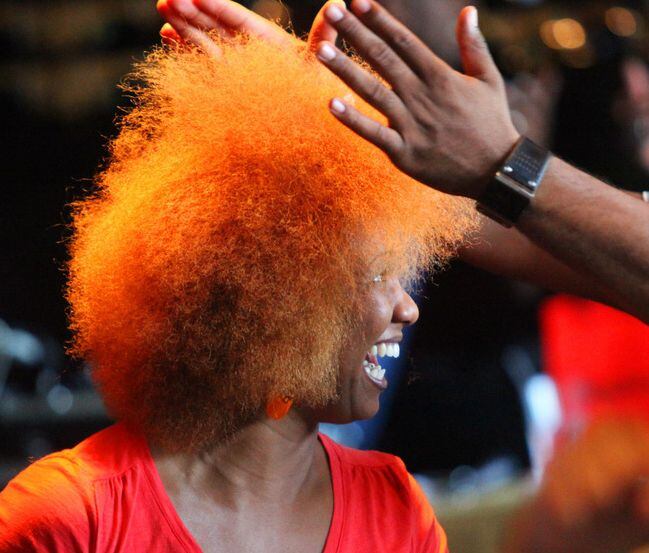 A woman smiles at her natural hair style.