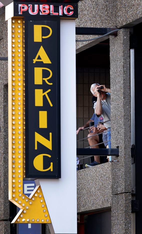 An NFL football fan uses a pair of binoculars to view the Canton Repository Grand Parade from a downtown Canton, Ohio parking garage, Saturday, August 7, 2021. The parade honored newly elected and former members of the Hall, including newcomers and former Dallas Cowboys players Cliff Harris, Drew Pearson and head coach Jimmy Johnson. (Tom Fox/The Dallas Morning News)