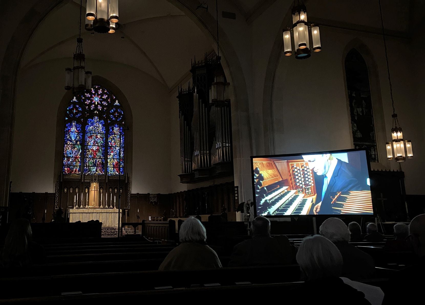 Organist Scott Dettra, playing in a chancel niche, is seen on a projection screen at Church...