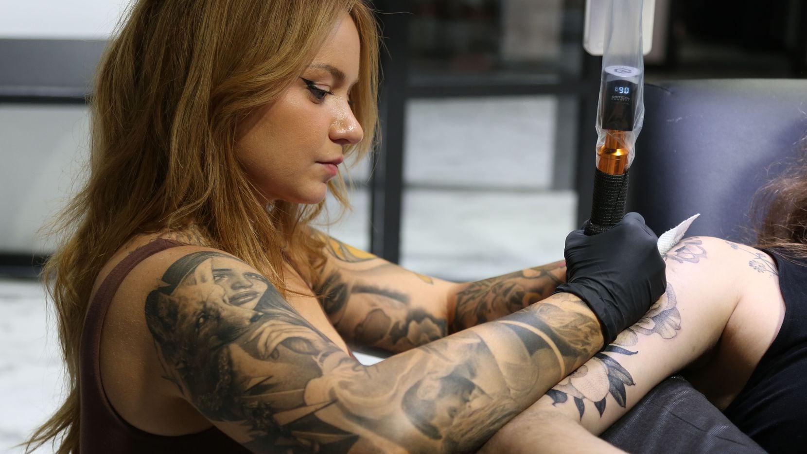 Deanna James, owner and resident artist of Eden Body Art Studios, tattoos a client. Eden...