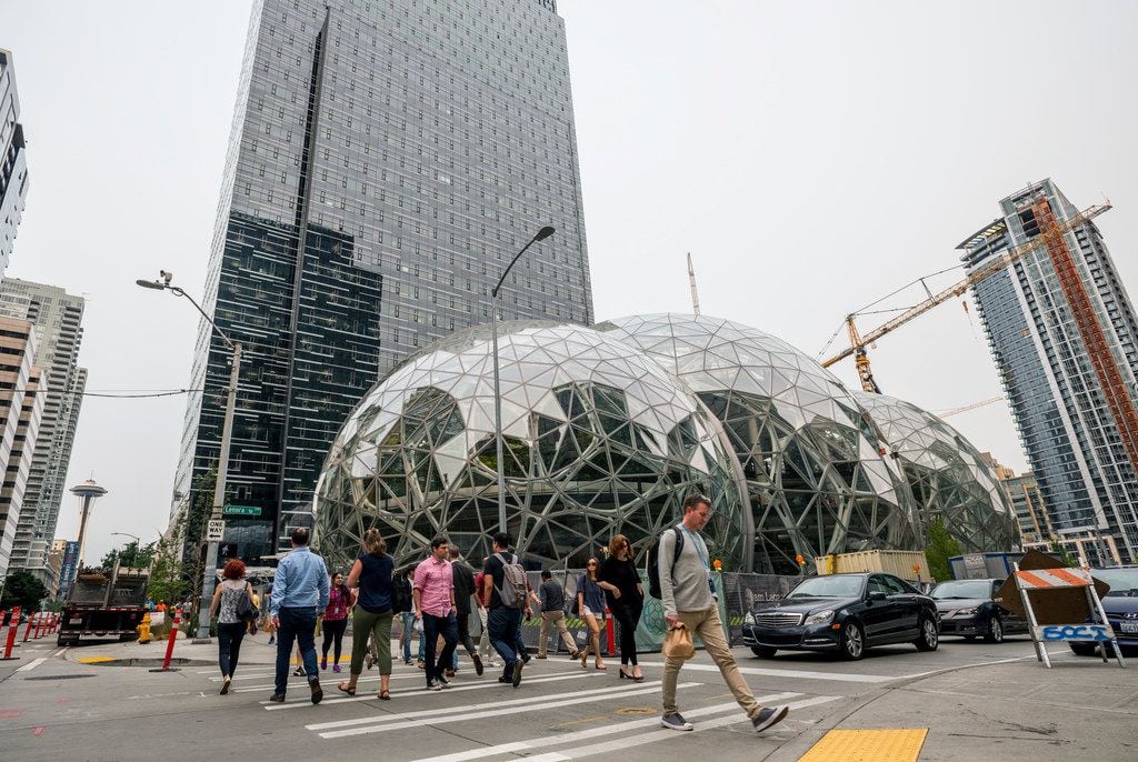 Pedestrians walk past a recently built trio of geodesic domes that are part of the Seattle...