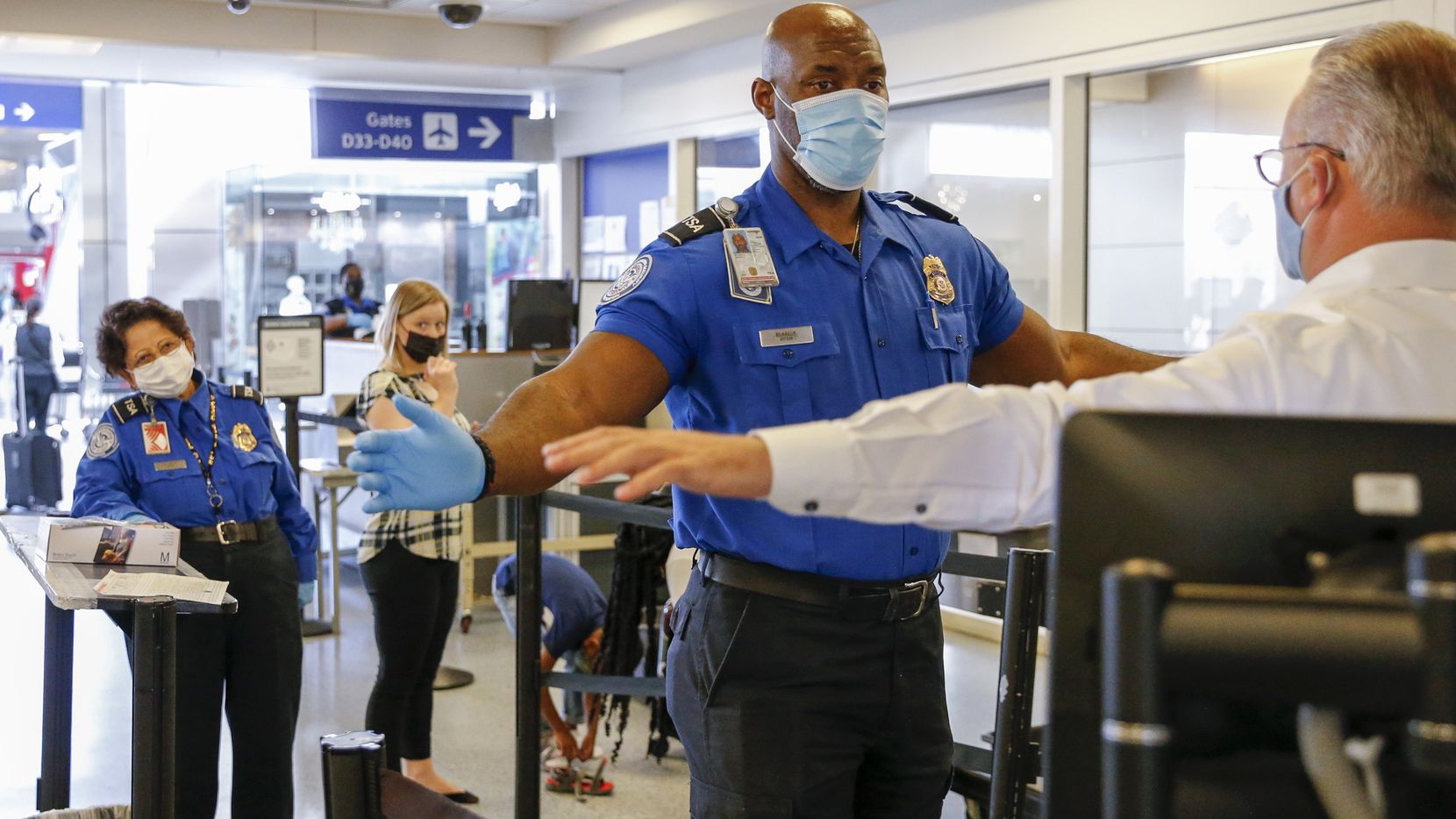 Transportation Security Officer Kevin Blakely assists a traveler during security screening...