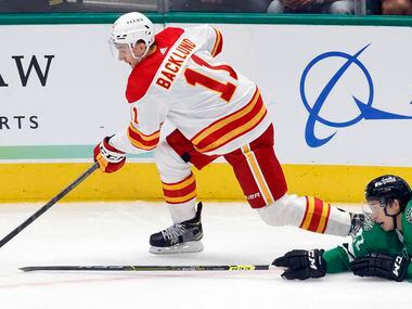 Dallas Stars left wing Jason Robertson (21) reaches for the puck as Calgary Flames center...
