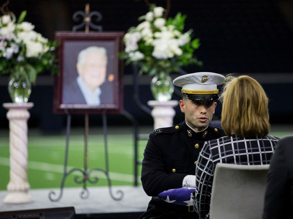 A member of the Marine Honor Guard presents a folded American flag to Robin Fry, daughter of...