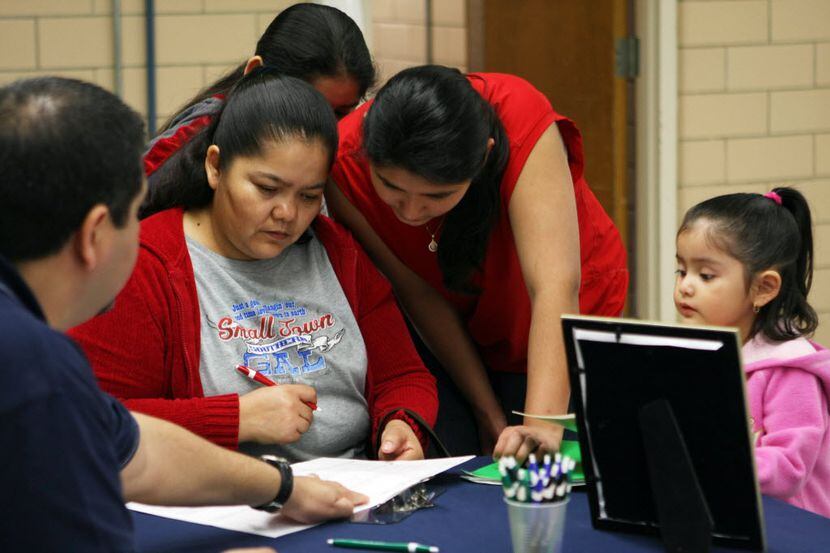 Maria Guerrero, right, with her children, listens to Aetna employee Louis Limas, left, as he...
