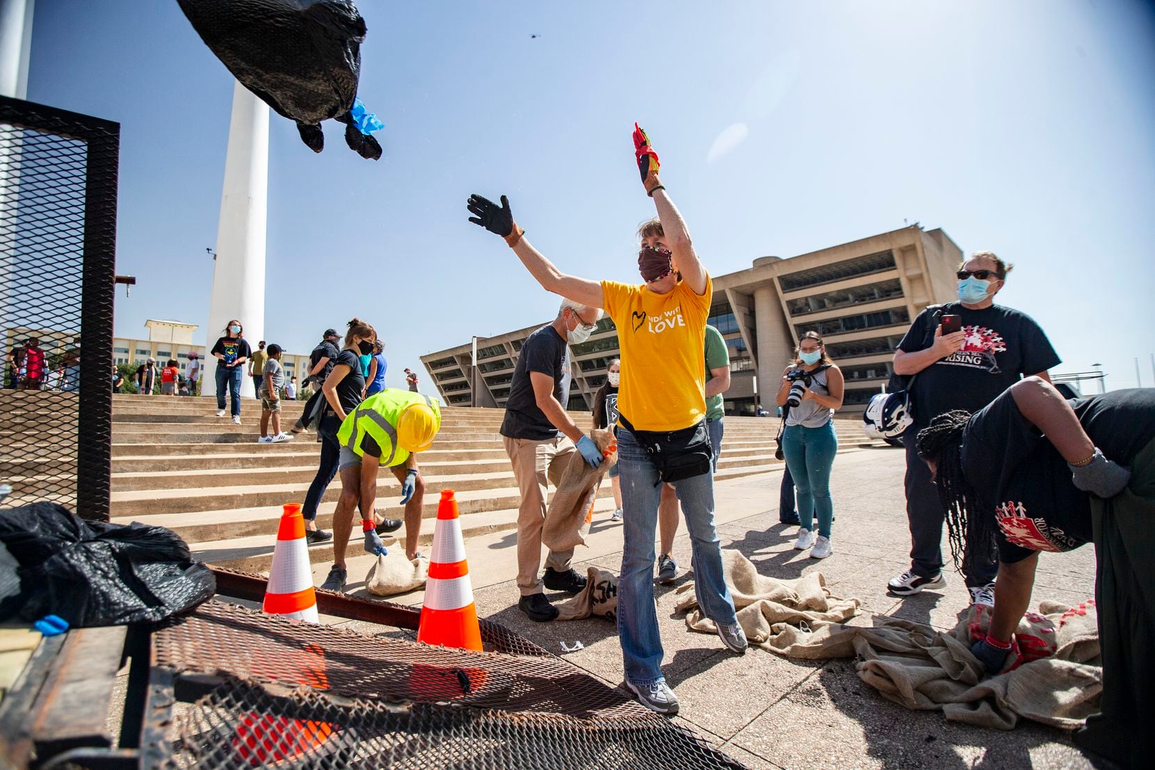Melinda Enochs-Baucom tosses a bag of shingles into the back of a City of Dallas trailer at Dallas City Hall, Monday, October 12, 2020. Enochs-Baucom and about 30 other demonstrators rallied on the city hall plaza to demand that the city finally begin to clean up “Shingle Mountain” in southeast Dallas. (Brandon Wade/Special Contributor)