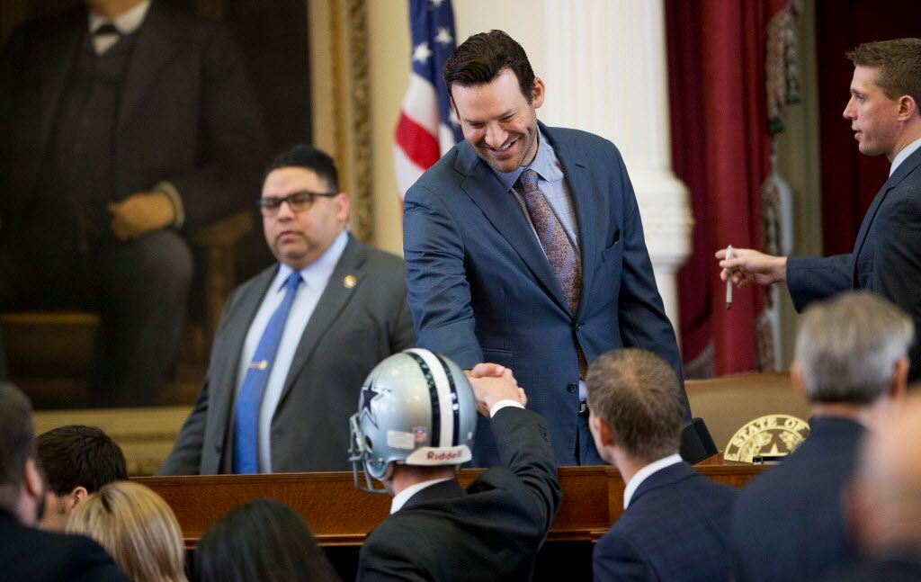 State Rep. Jeff Leach, R-Plano, wearing a football helmet, shakes hands with former Dallas...