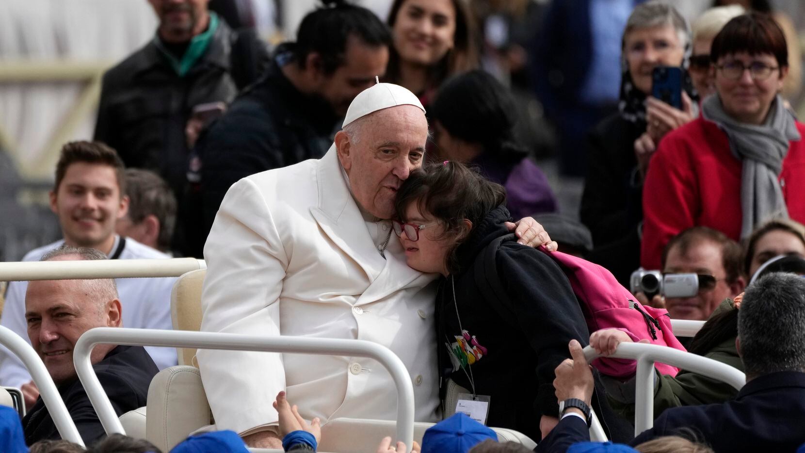 El papa Francisco abraza a una niña al finalizar su audiencia general semanal en la Plaza de...