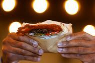 Dallas restaurant operator Jude Akpunku holds Miznon's cheeseburger pita, a popular order in...