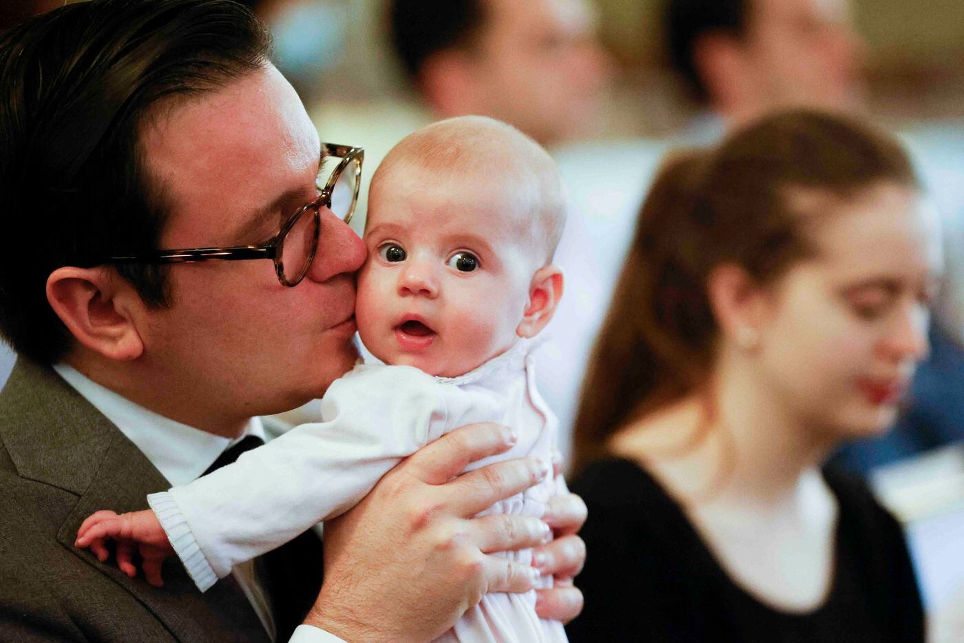 Four-month-old Cecilia Dobbs gets a kiss from her father Tyler as her mother Isabel prays...