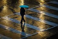 A pedestrian bundles up against a cold rain while crossing Nowitzki Way at Victory Avenue as...