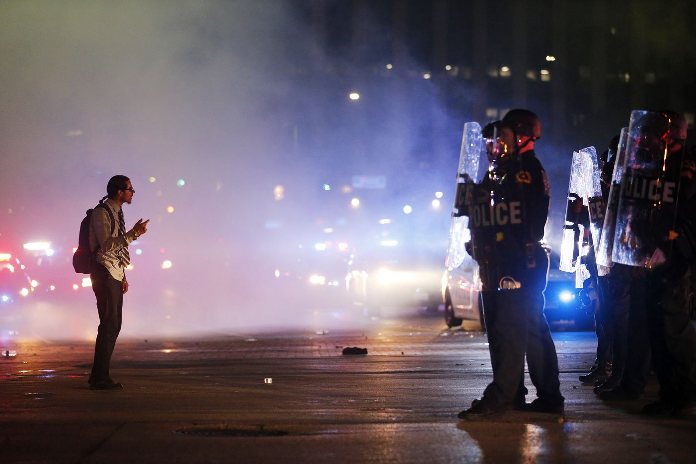 A protestor stands in the middle of the tear gas confronting tactical officers at the...