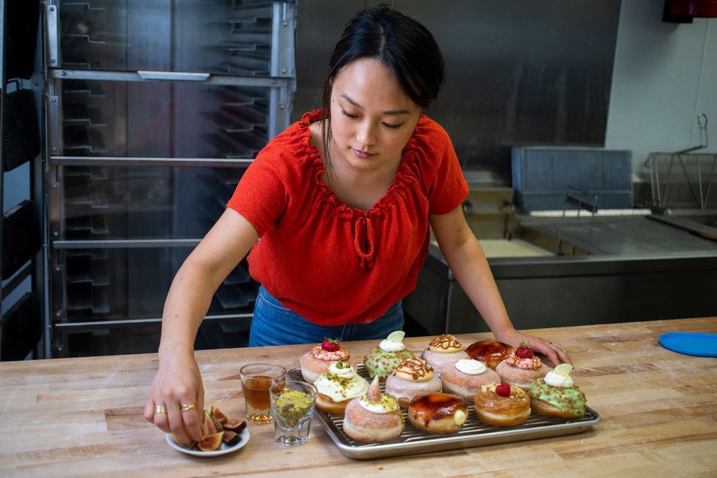 Jinny Cho, owner of Detour Doughnuts and Coffee, puts finishing touches on an assortment of...
