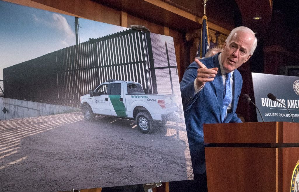Senate Majority Whip John Cornyn of Texas points to a poster with an image of a barrier on...